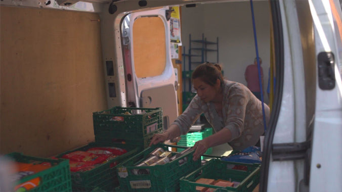 volunteer carrying a box of food during a charity video production shoot