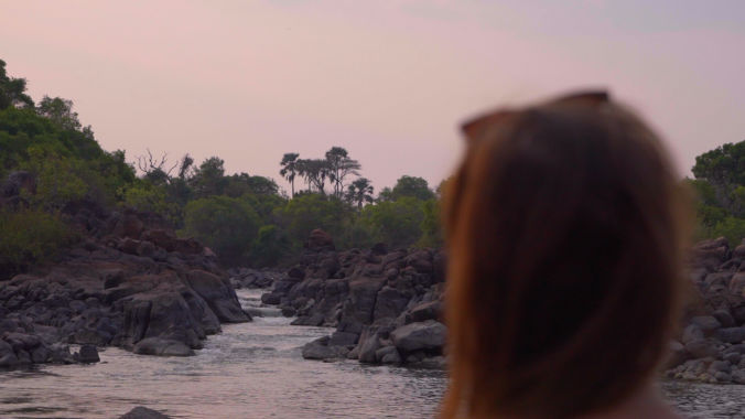 A person gazing at a river view during a pink sunset.